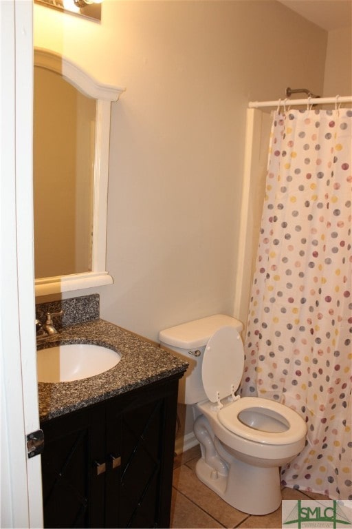 bathroom featuring tile patterned flooring, vanity, curtained shower, and toilet