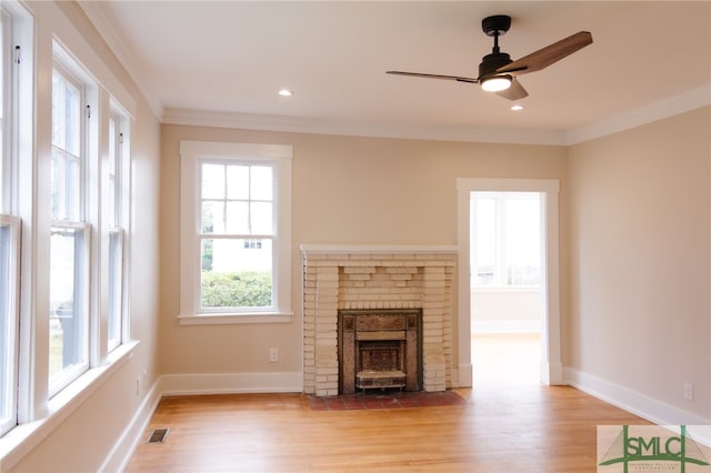 unfurnished living room featuring a brick fireplace, ceiling fan, light hardwood / wood-style flooring, and ornamental molding