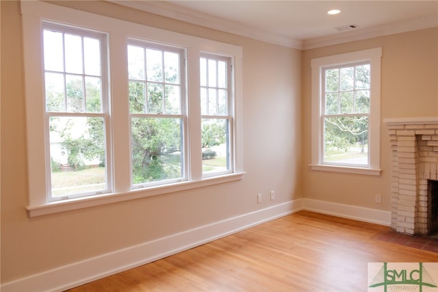 unfurnished living room with light hardwood / wood-style floors, crown molding, and a fireplace