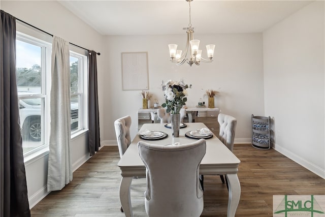 dining space with hardwood / wood-style floors and a notable chandelier