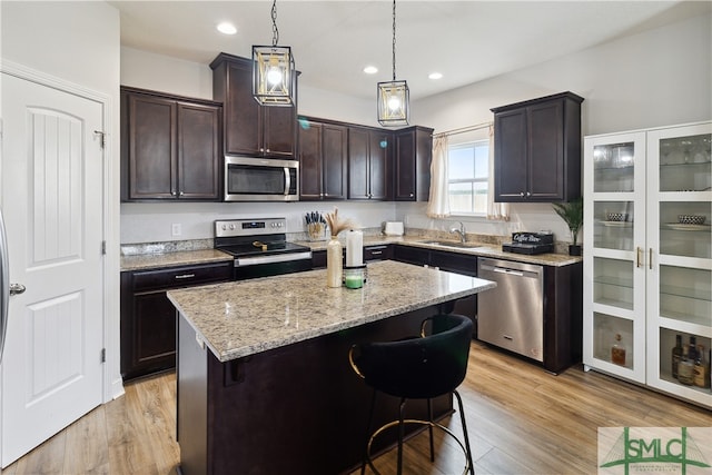 kitchen featuring a center island, stainless steel appliances, a kitchen breakfast bar, light hardwood / wood-style floors, and dark brown cabinets