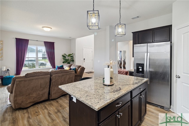 kitchen with stainless steel fridge, a kitchen island, light wood-type flooring, and hanging light fixtures