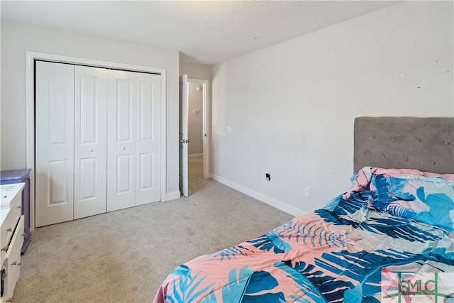 bedroom with light colored carpet, a textured ceiling, and a closet