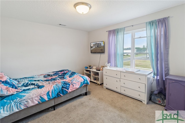 bedroom featuring a textured ceiling and light colored carpet