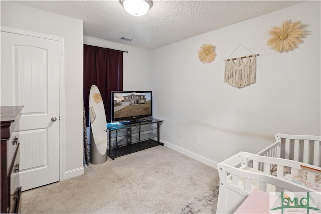 carpeted bedroom with a crib and a textured ceiling