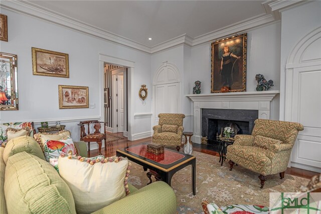 living room with hardwood / wood-style flooring, ornamental molding, and a high end fireplace