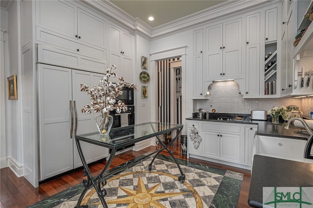 kitchen featuring paneled fridge, ornamental molding, dark wood-type flooring, and sink