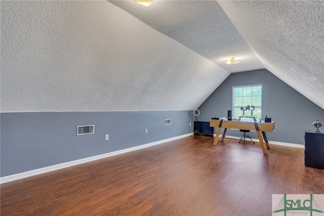 bonus room with dark hardwood / wood-style floors, lofted ceiling, and a textured ceiling