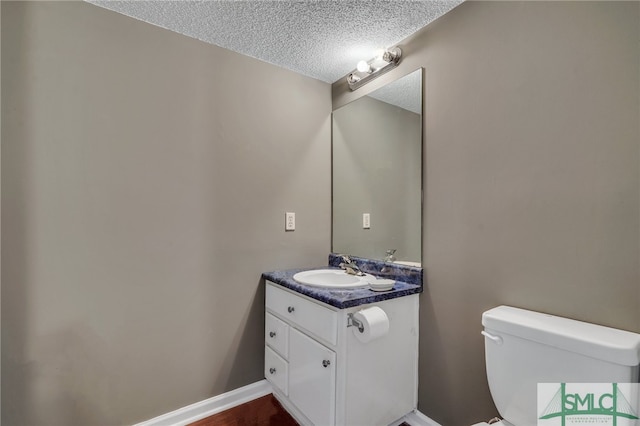 bathroom featuring vanity, toilet, wood-type flooring, and a textured ceiling