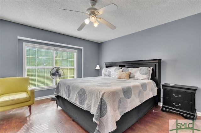 bedroom with ceiling fan, dark wood-type flooring, and a textured ceiling