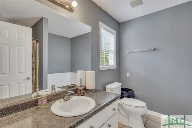 bathroom with tile patterned flooring, vanity, toilet, and a textured ceiling