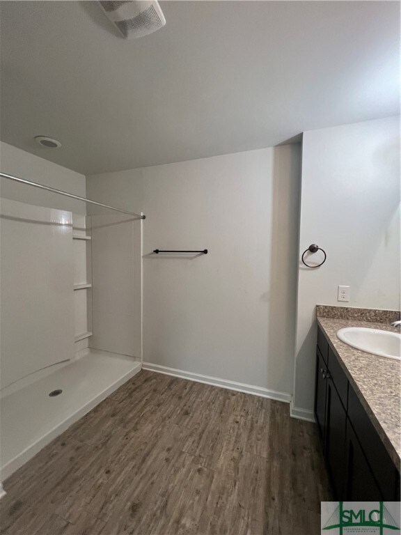 bathroom featuring a shower, vanity, and wood-type flooring