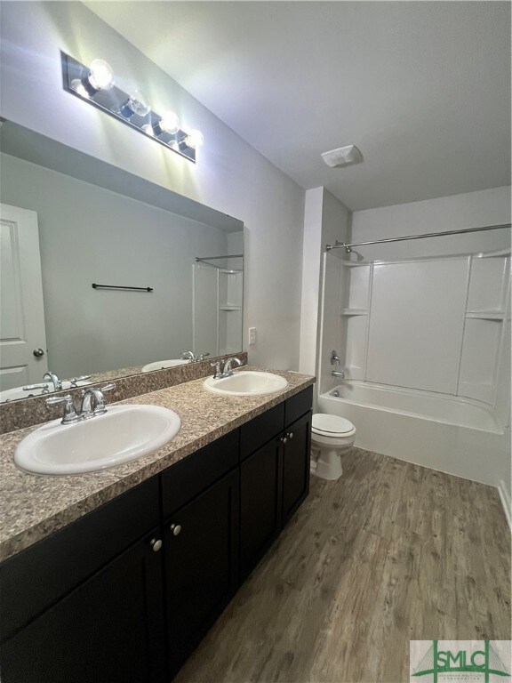 full bathroom featuring wood-type flooring, vanity, bathing tub / shower combination, and toilet