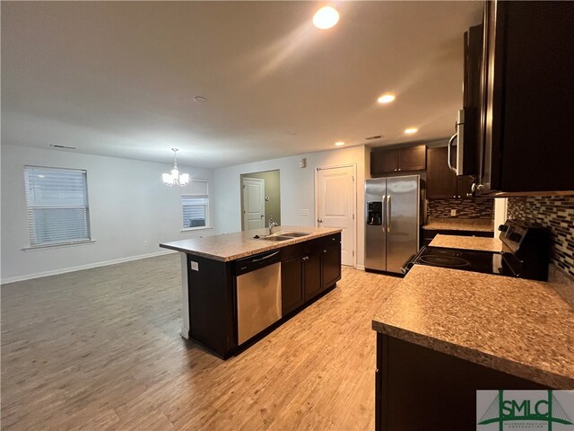 kitchen featuring sink, light hardwood / wood-style flooring, an island with sink, pendant lighting, and appliances with stainless steel finishes