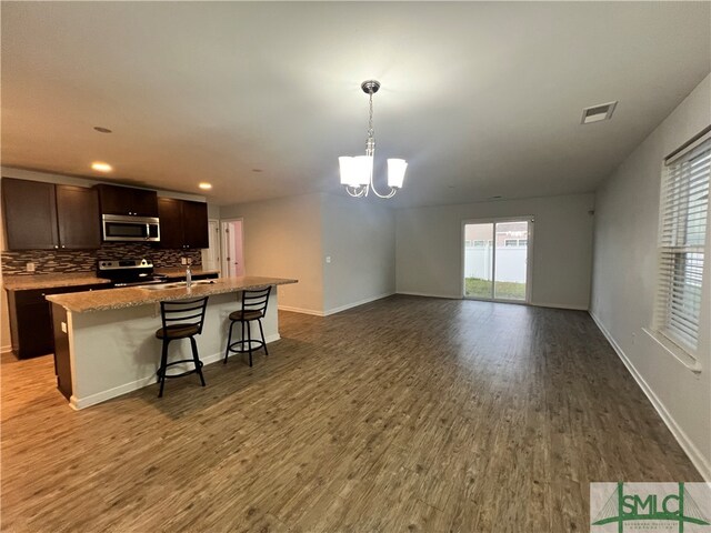 kitchen with a center island with sink, a breakfast bar area, decorative light fixtures, wood-type flooring, and stainless steel appliances