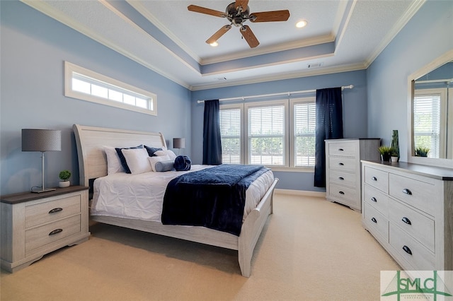 bedroom with light colored carpet, ceiling fan, crown molding, and a tray ceiling