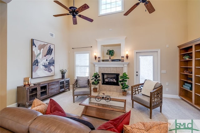 carpeted living room featuring a wealth of natural light, a tile fireplace, and a high ceiling