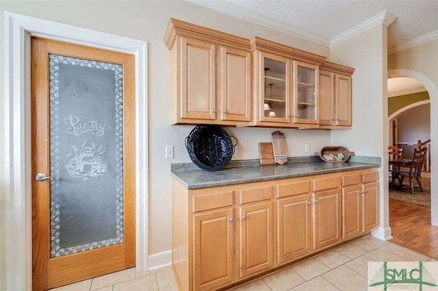 kitchen featuring crown molding, light tile patterned flooring, and a textured ceiling