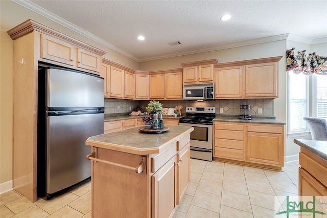 kitchen with appliances with stainless steel finishes, light tile patterned floors, a kitchen island, and crown molding