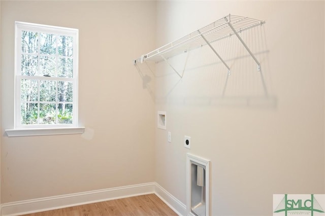 clothes washing area with washer hookup, light wood-style floors, electric dryer hookup, laundry area, and baseboards