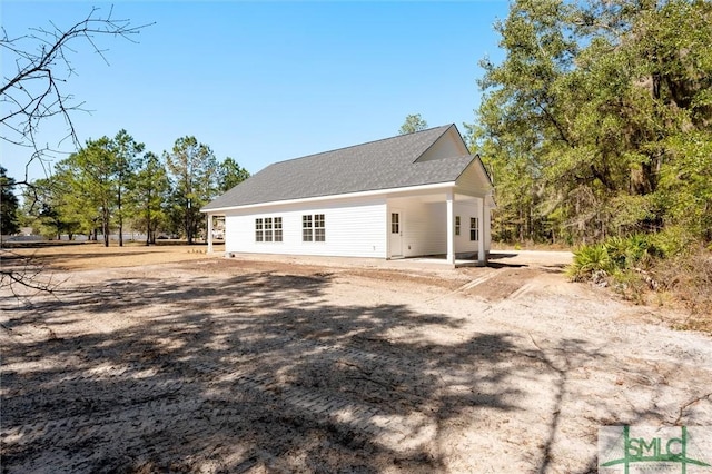 view of home's exterior featuring roof with shingles and a patio