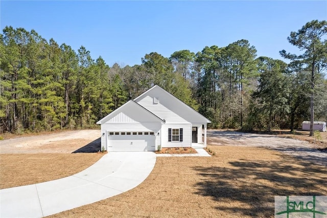 view of front facade featuring a garage, concrete driveway, and a forest view