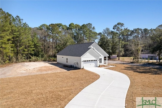 view of side of home featuring concrete driveway and roof with shingles