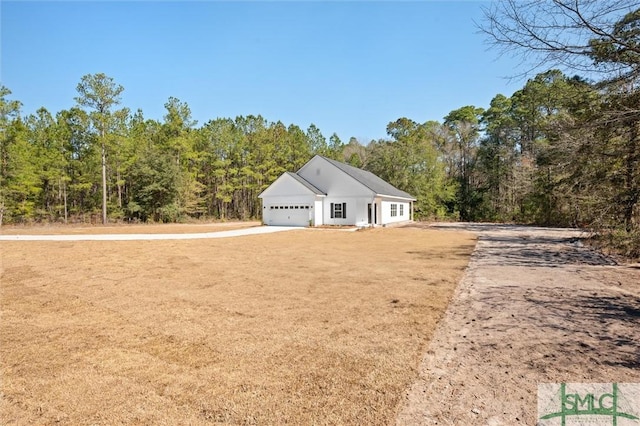 view of front of house with driveway, a view of trees, and an attached garage