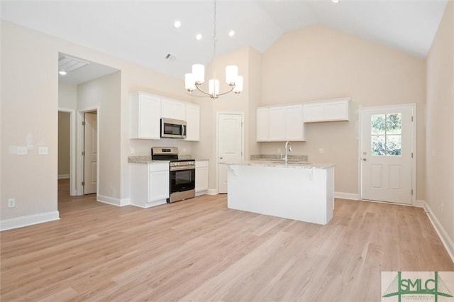 kitchen with high vaulted ceiling, light stone counters, white cabinetry, light wood-style floors, and appliances with stainless steel finishes