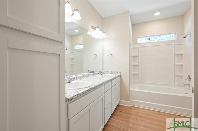 full bathroom featuring double vanity, tub / shower combination, a sink, and wood finished floors