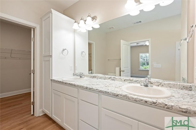 bathroom with double vanity, wood finished floors, a sink, and visible vents