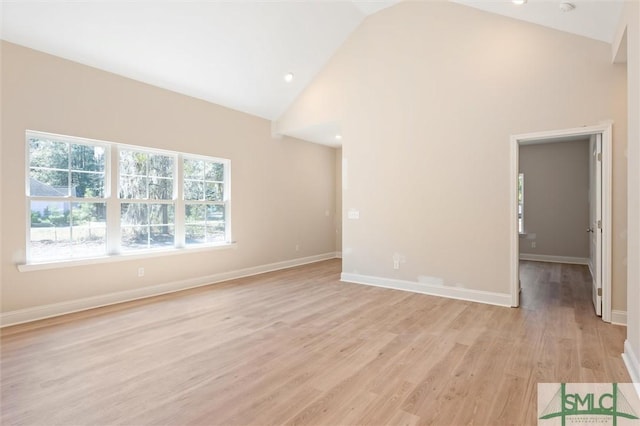 unfurnished living room featuring high vaulted ceiling, light wood-type flooring, and baseboards