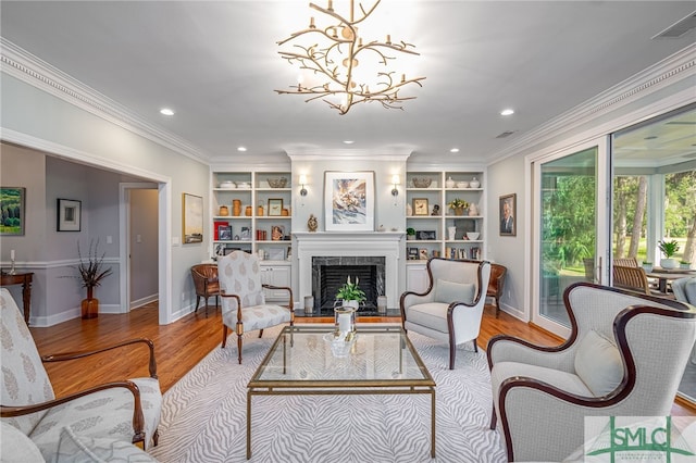 living room with built in shelves, light hardwood / wood-style floors, an inviting chandelier, and ornamental molding