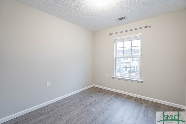 unfurnished room with hardwood / wood-style flooring and a textured ceiling