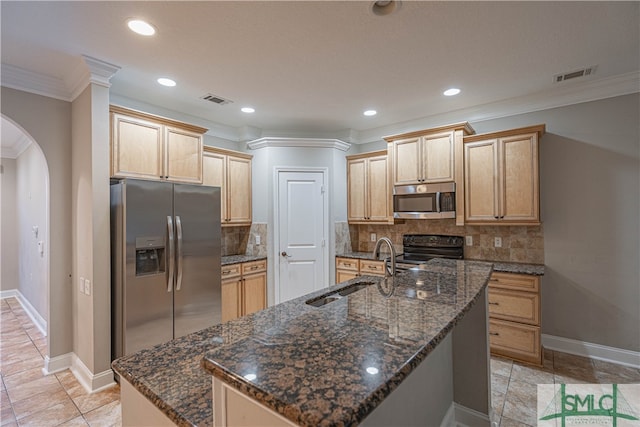 kitchen featuring stainless steel appliances, light brown cabinetry, and an island with sink