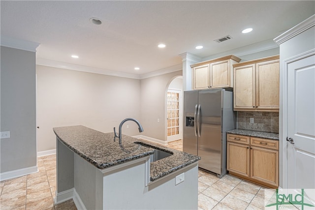 kitchen featuring sink, a kitchen island with sink, stainless steel refrigerator with ice dispenser, ornamental molding, and dark stone counters