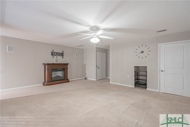 unfurnished living room with light carpet, ceiling fan, and a textured ceiling