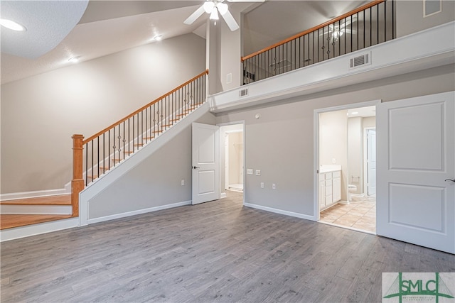 unfurnished living room featuring high vaulted ceiling, ceiling fan, and light wood-type flooring