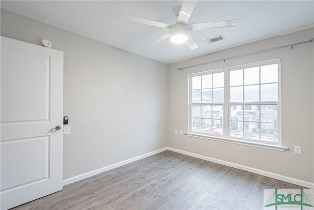 empty room with ceiling fan, light hardwood / wood-style flooring, and a textured ceiling