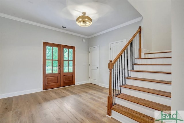 entrance foyer with ornamental molding, french doors, and light hardwood / wood-style flooring