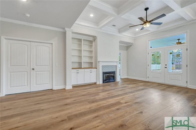 unfurnished living room with coffered ceiling, beamed ceiling, a fireplace, and light hardwood / wood-style floors