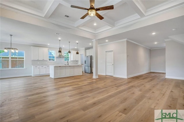 unfurnished living room with light hardwood / wood-style floors, coffered ceiling, ceiling fan with notable chandelier, beamed ceiling, and decorative columns