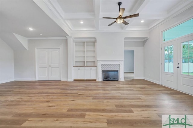 unfurnished living room featuring beam ceiling, french doors, a tiled fireplace, coffered ceiling, and light wood-type flooring