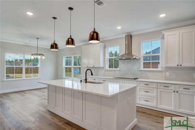 kitchen featuring a center island with sink, extractor fan, pendant lighting, white cabinets, and black electric cooktop