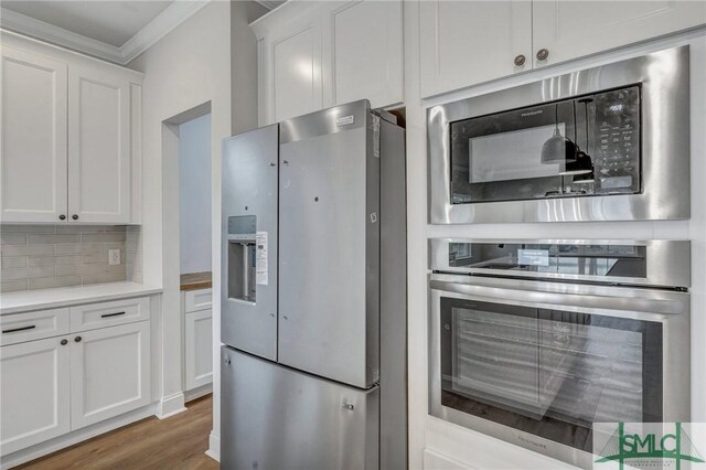 3250 Midland Rd, Guyton, GA 31312 - kitchen with wood finished floors, white cabinets, appliances with stainless steel finishes, tasteful backsplash, and ornamental molding