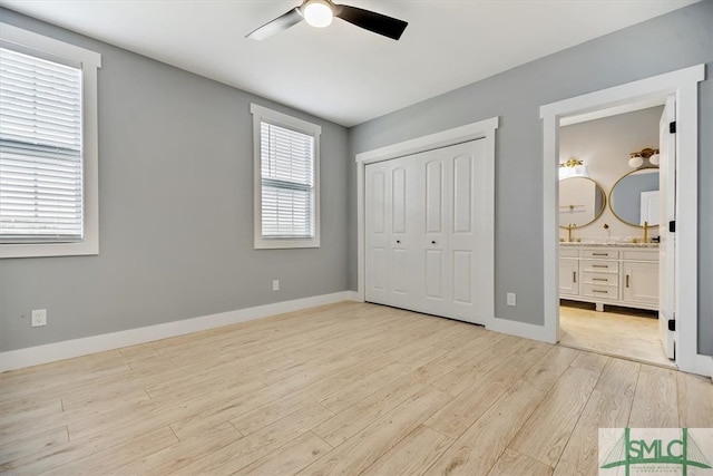 unfurnished bedroom with light wood-type flooring, sink, a closet, ceiling fan, and connected bathroom