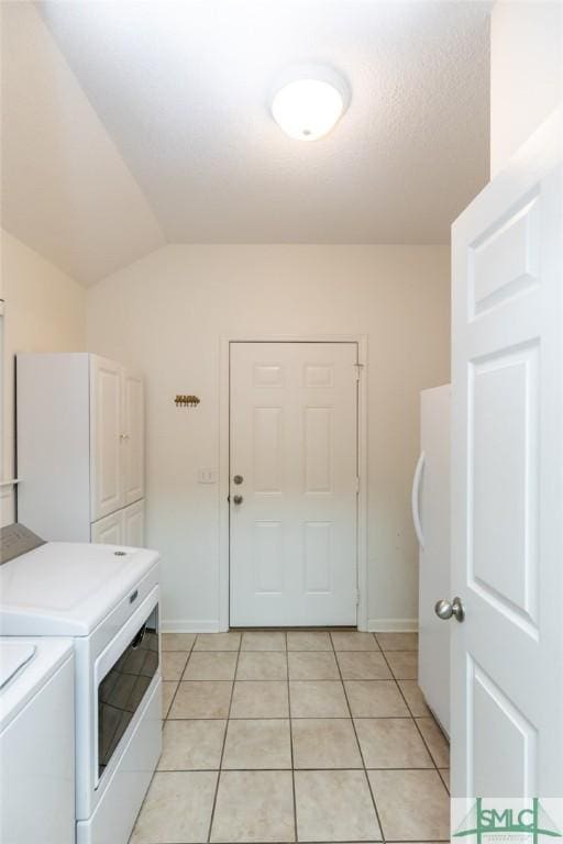 laundry room with washer and dryer, cabinets, and light tile patterned floors