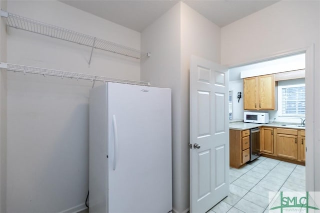 kitchen featuring sink, light tile patterned flooring, and white appliances