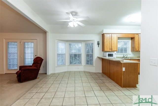 kitchen with kitchen peninsula, light carpet, plenty of natural light, and ceiling fan