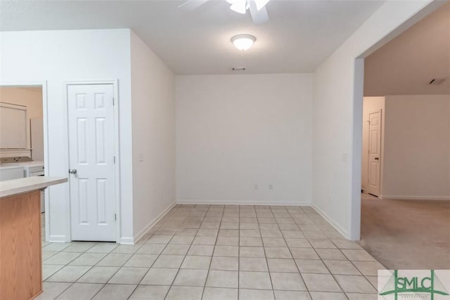 unfurnished dining area with light carpet, ceiling fan, and washing machine and clothes dryer